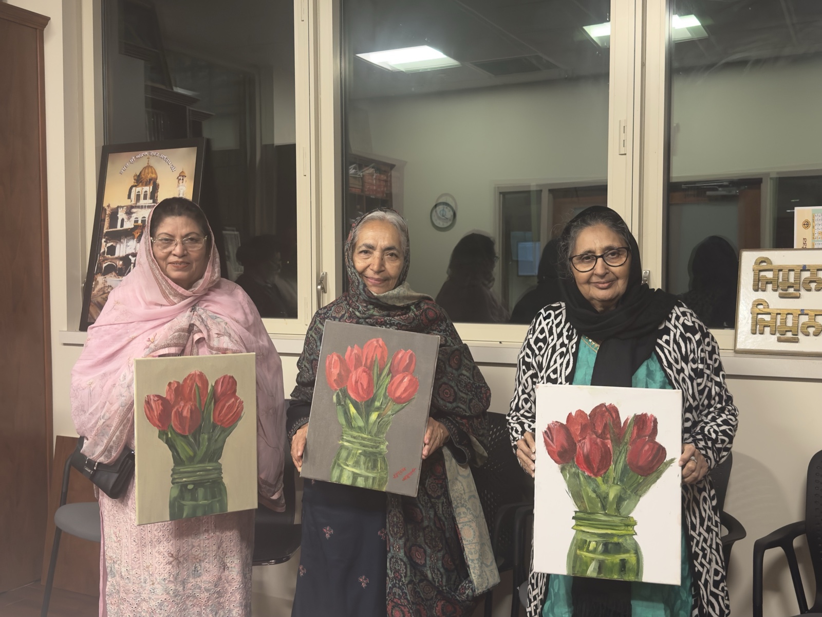 Three students holding the tulip paintings they made in class