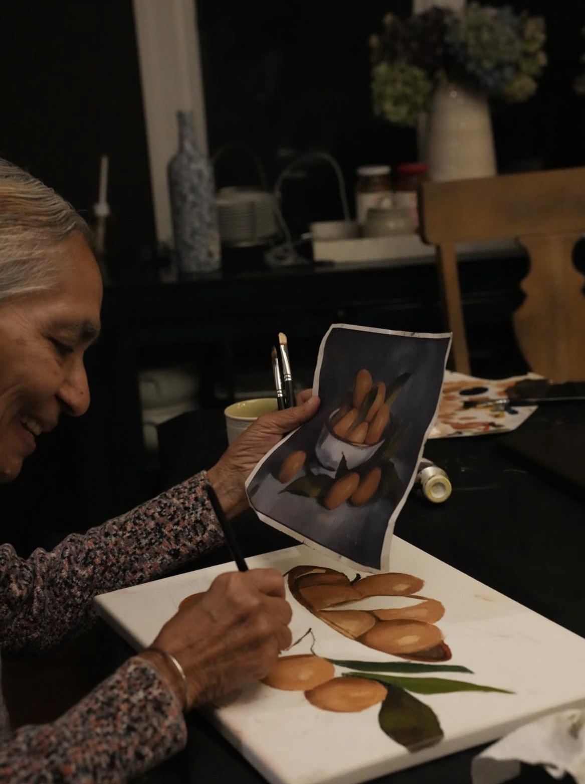 A student comparing her painting to the reference, laughing